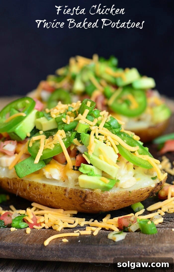 Zesty Fiesta Chicken Stuffed Potatoes 2 Delicious Fiesta Chicken Twice Baked Potatoes, beautifully plated and topped with melted cheese, vibrant green onions, fresh jalapeno slices, and creamy avocado chunks.