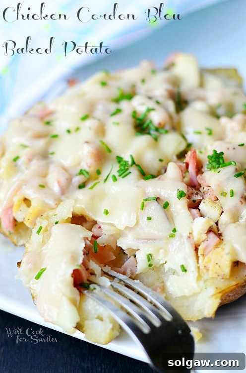 Zesty Fiesta Chicken Stuffed Potatoes 11 A perfectly prepared Chicken Cordon Bleu Baked Potato, stuffed with chicken, ham, and cheese, garnished with fresh herbs, held on a fork ready to be enjoyed.