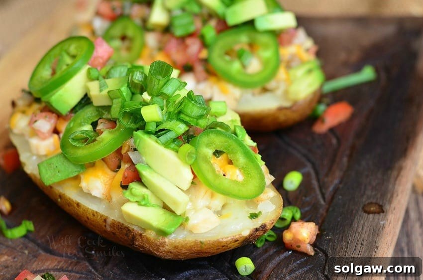Zesty Fiesta Chicken Stuffed Potatoes 4 Close-up photograph of a perfectly prepared Fiesta Chicken Twice Baked Potato, showcasing the rich texture of the potato and the colorful toppings of melted cheese, vibrant green onions, and fresh avocado.