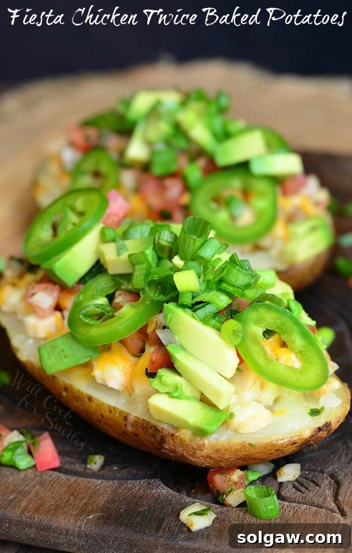 Zesty Fiesta Chicken Stuffed Potatoes 7 An appetizing top-down view of several Fiesta Chicken Twice Baked Potatoes arranged for serving, garnished generously with vibrant green onions, a sprinkle of fresh cheese, spicy jalapeno slices, and rich avocado pieces.