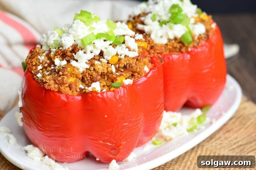 Two red bell peppers stuffed with a chorizo and quinoa mixture, served on a plate