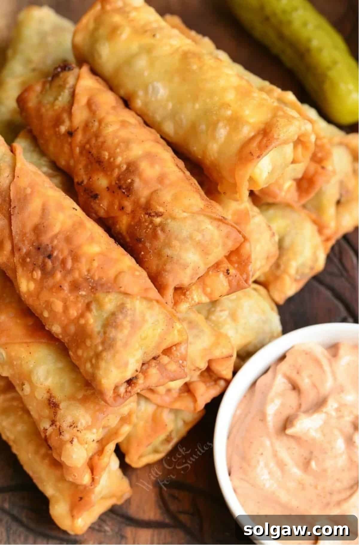 fried cheeseburger egg rolls stacked next to a dip.