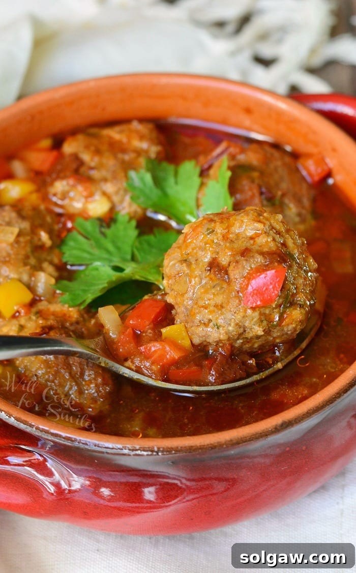 Grandma's Albondigas Soup 5 Mexican Meatballs Soup in a bowl with a spoon lifting a meatball out