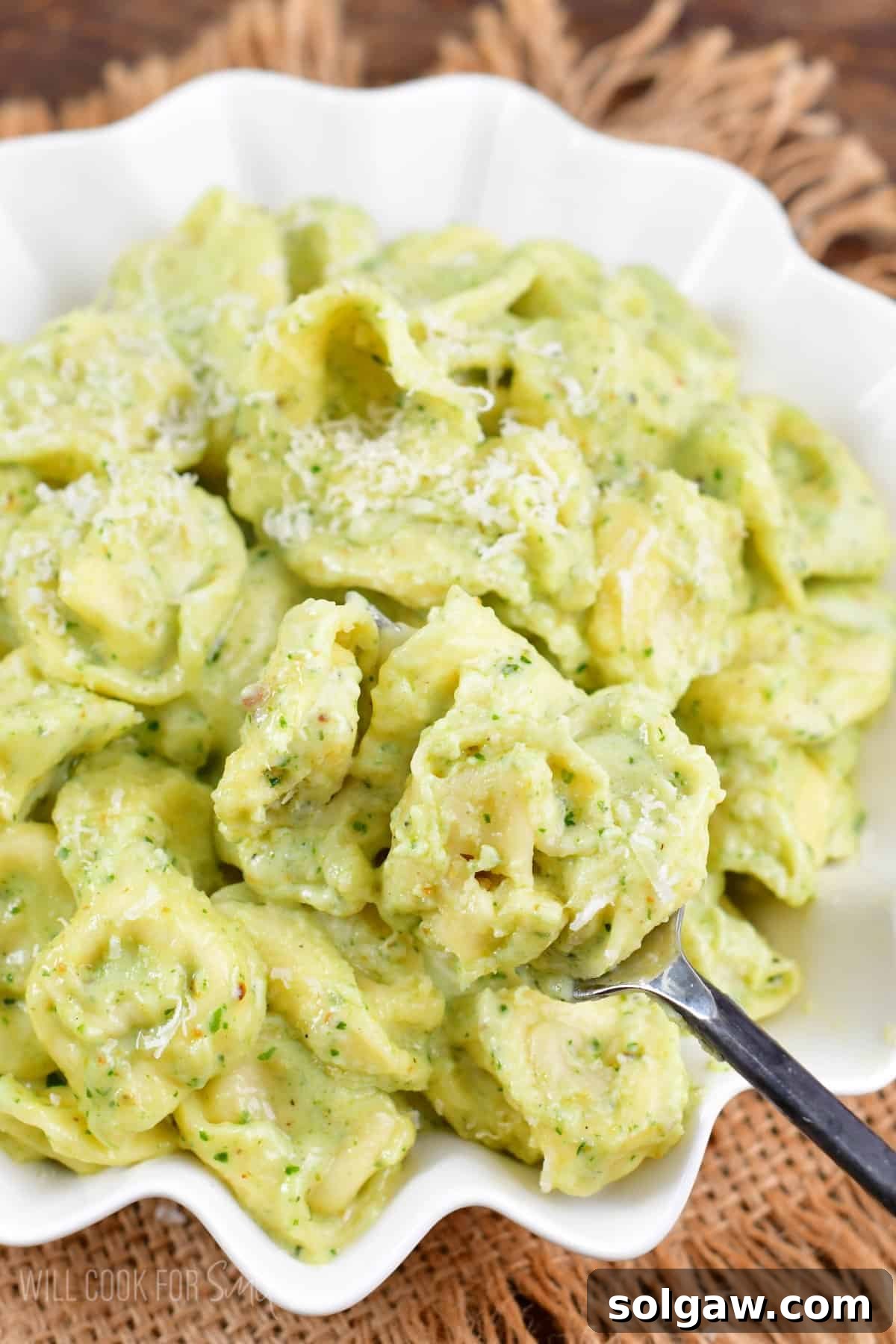 Creamy Pesto Alfredo Tortellini 2 Pesto Alfredo Tortellini in a bowl scooped onto a fork, showcasing the creamy, green sauce and plump tortellini.