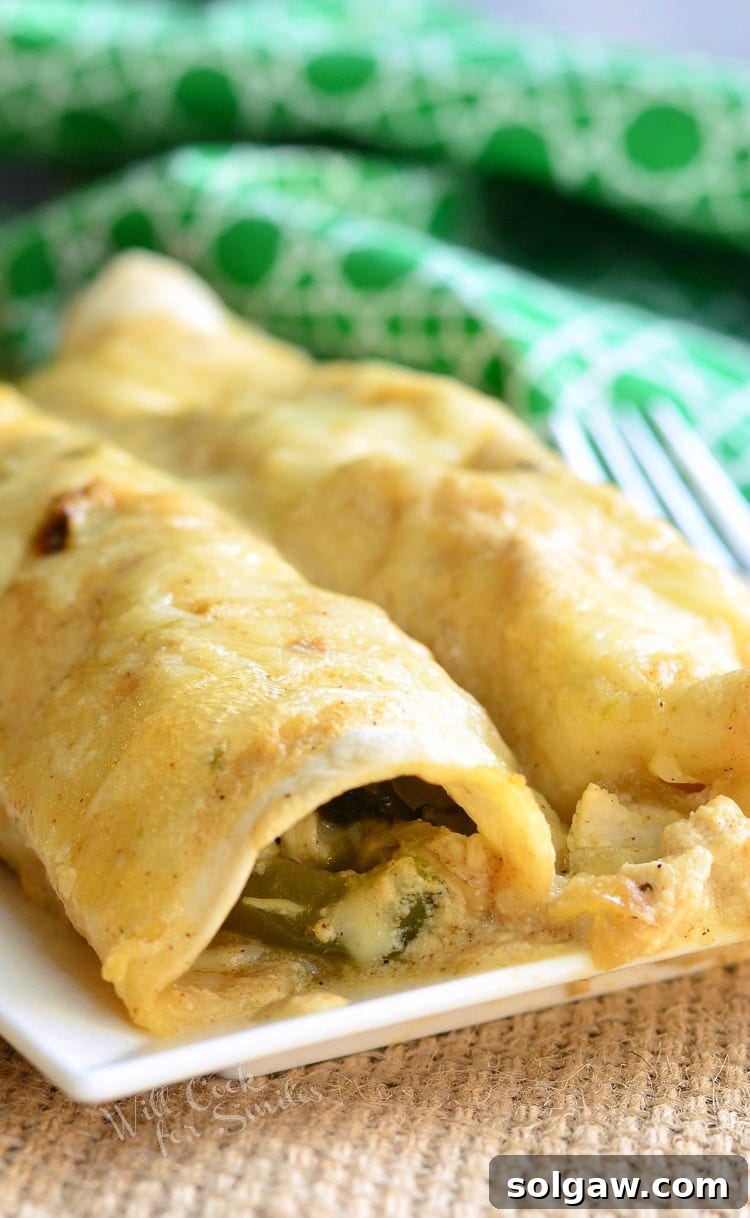 Smoky Poblano Chicken Enchiladas 2 Roasted Poblano and Chicken Enchiladas on a white plate, ready to be enjoyed.