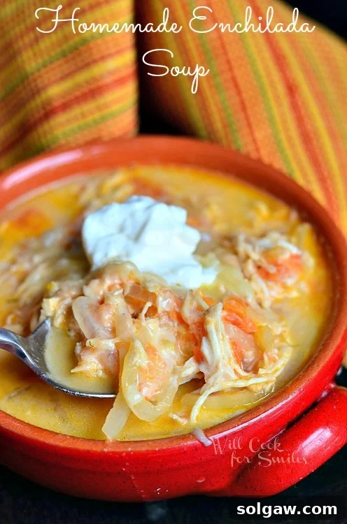 Smoky Poblano Chicken Enchiladas 8 Homemade Enchilada Soup in a red bowl with a spoon and sour cream on top, garnished with cilantro.