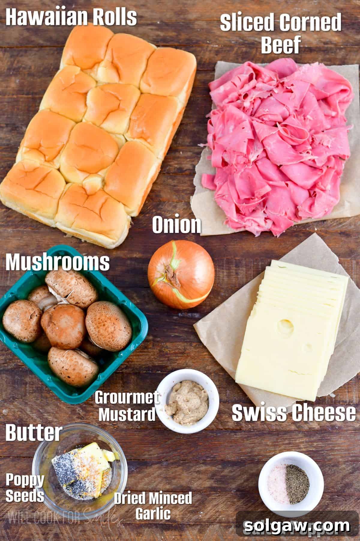 Labeled ingredients for corned beef sliders laid out on a rustic wood surface, including rolls, corned beef, Swiss cheese, mustard, onions, mushrooms, butter, garlic, and poppy seeds.