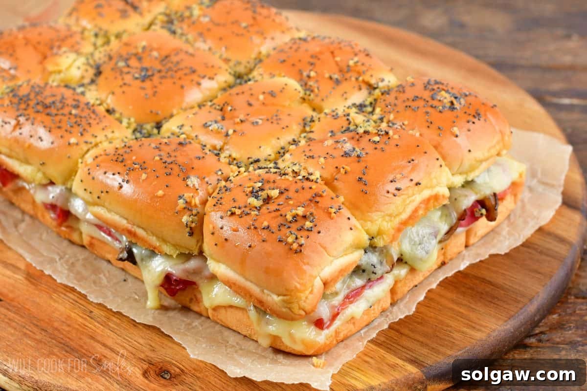 Freshly baked corned beef sliders arranged neatly on a piece of wax paper, set on a rustic wood cutting board, ready for serving.