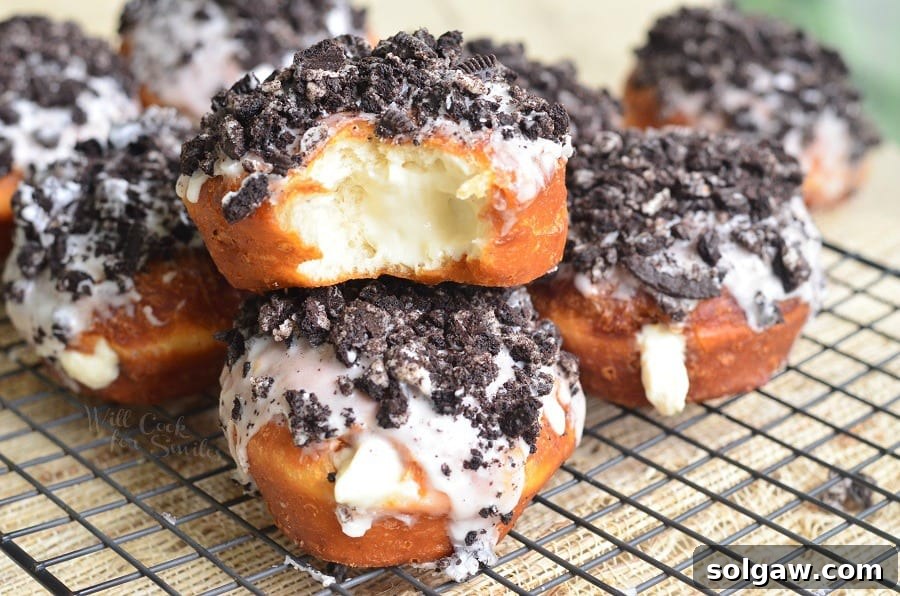 Close-up of freshly made Oreo Cheesecake Doughnuts, generously coated with a sweet glaze and sprinkled with crushed Oreo cookies.