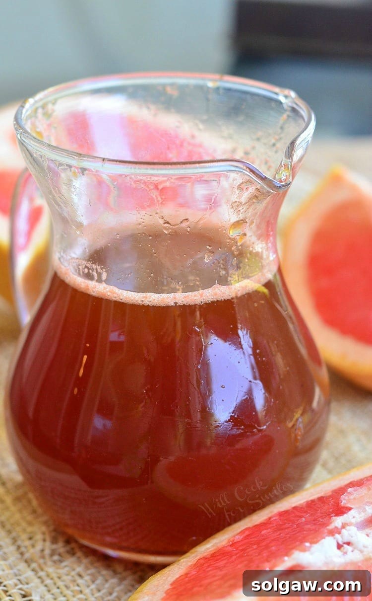 Homemade Grapefruit Syrup in a glass container, showcasing its beautiful, clear consistency.