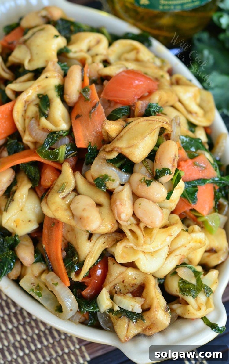 Top view of Tuscan Tortellini Salad with carrots, onions, and tomatoes, a fresh and hearty meal.