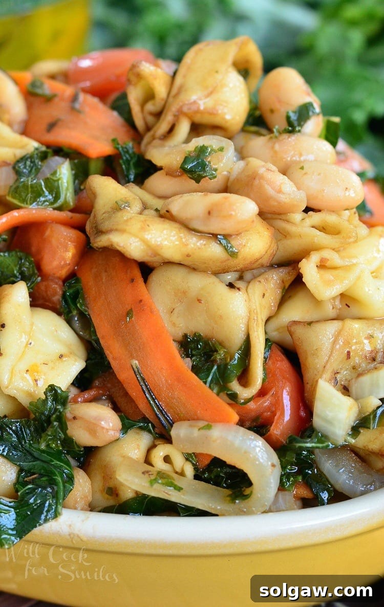 Tuscan Tortellini Salad with carrots, onions, and tomatoes, presented in a vibrant yellow bowl.