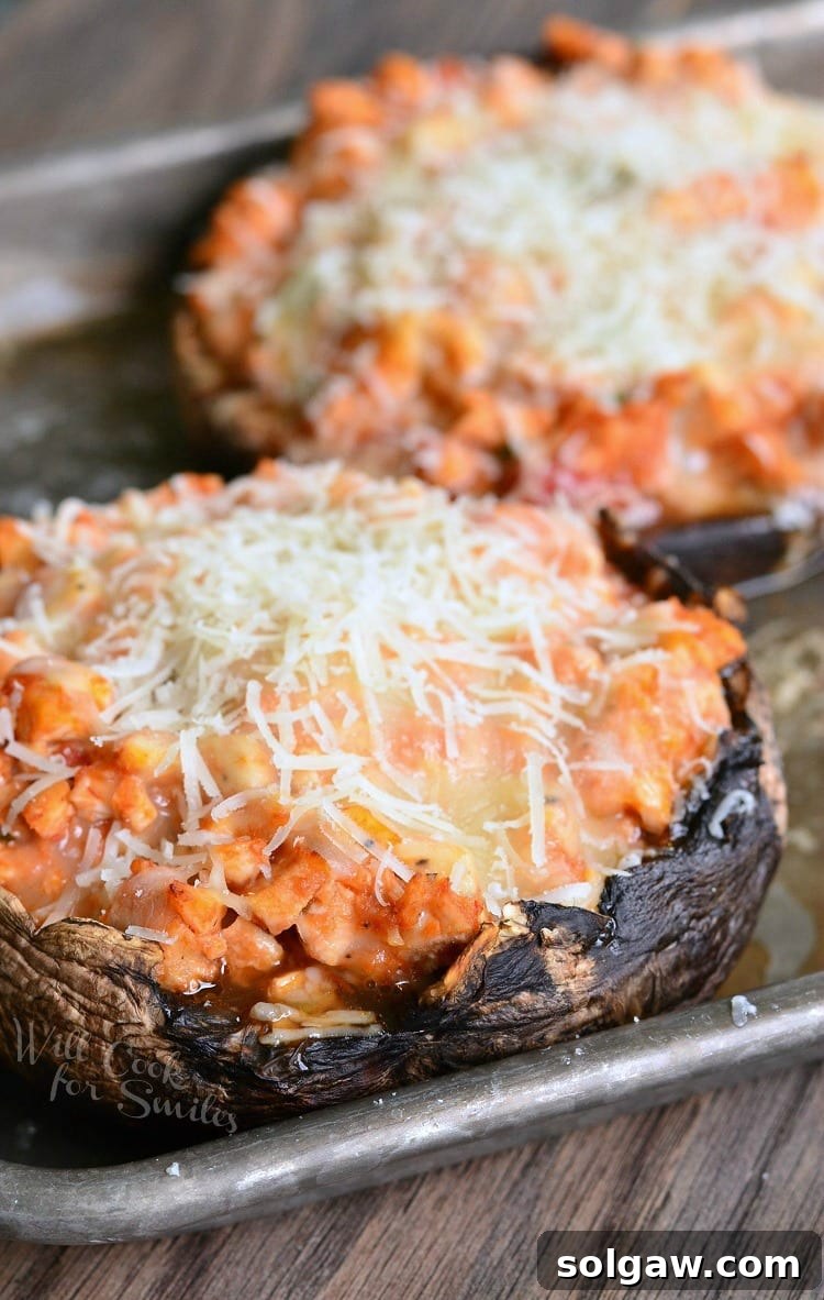 Two Chicken Parmesan Stuffed Portobello mushrooms ready for baking on a sheet