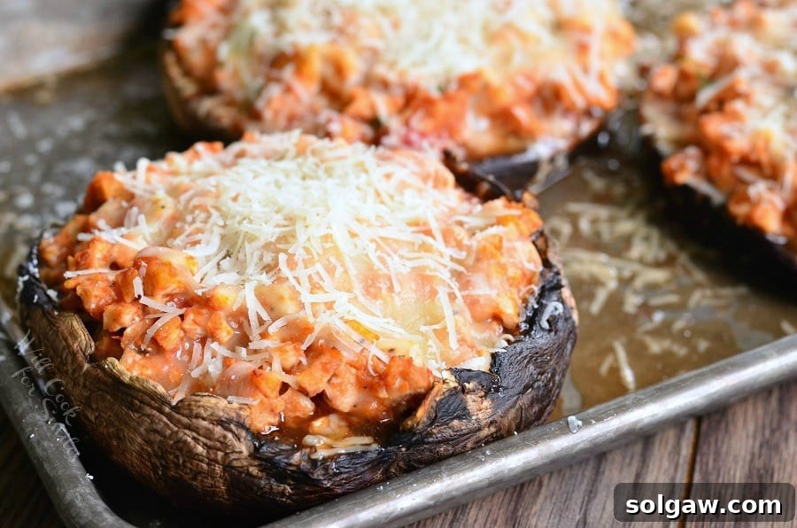 Three Chicken Parmesan Stuffed Portobello mushrooms on a baking sheet, close-up