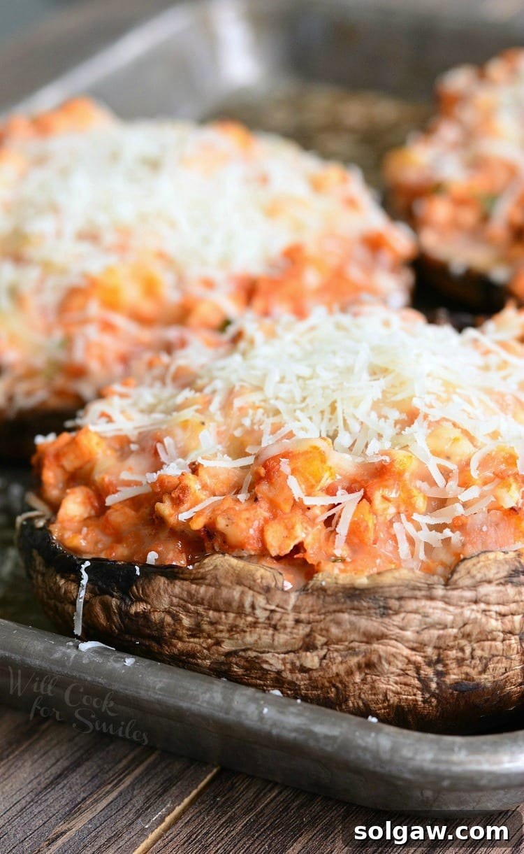 3 chicken parmesan stuffed portobello on a baking sheet tray