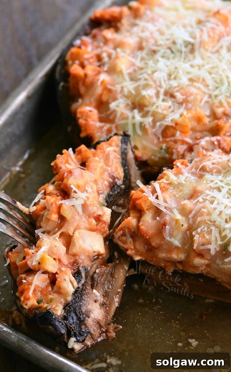 A Chicken Parmesan Stuffed Portobello mushroom on a baking sheet, with a fork taking a piece