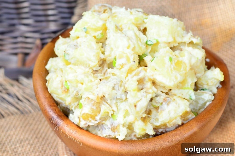 Savory Roasted Garlic Asiago Potato Salad 5 Wooden bowl filled with roasted garlic asiago potato salad on a tan cloth as viewed close up