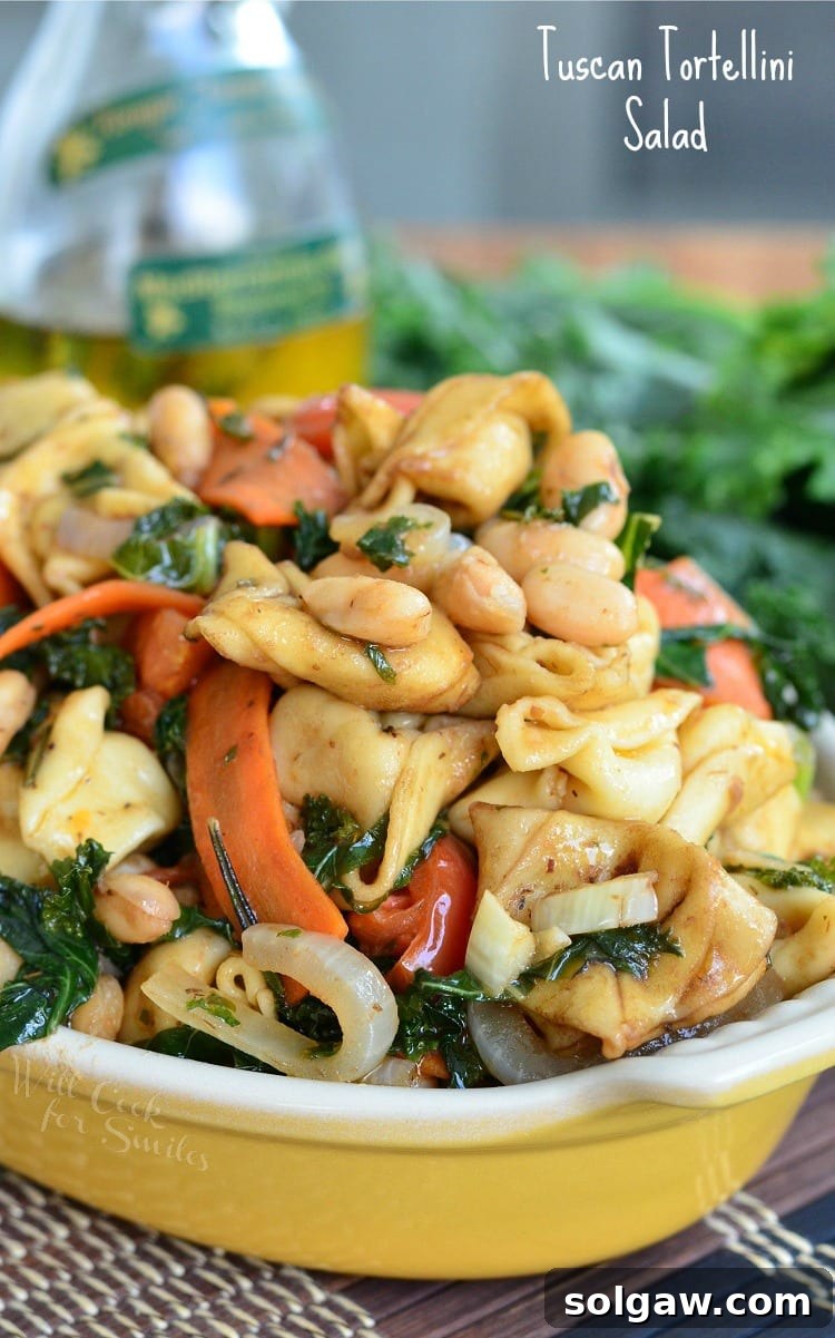 Tuscan Tortellini Salad with carrots, onions, and spinach in a yellow bowl 