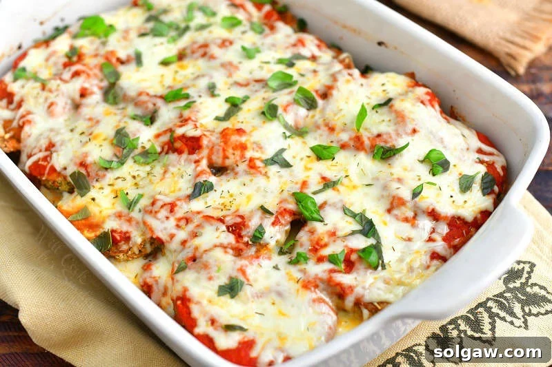 Irresistible Baked Eggplant Parmesan 6 closer view of baked eggplant parmesan in a white casserole dish on to of a burlap towel