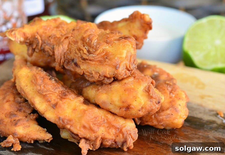 Fiery Sriracha Chicken with Sweet Honey Dip 5 Chicken Tenders stacked up on a cutting board
