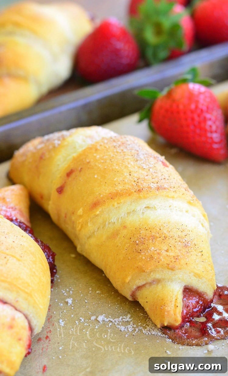 Strawberry Vanilla Crescent Rolls on a baking sheet with strawberries in the background 