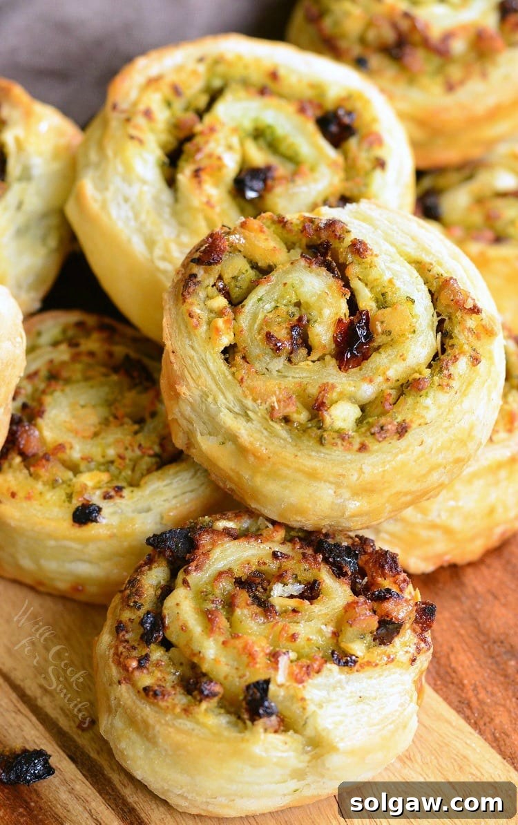 stack of chicken and sun dried tomato pinwheels on a wooden cutting board as seen from above.
