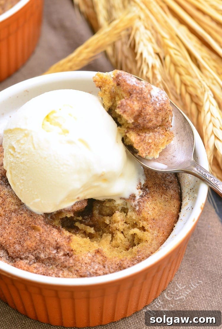 Pumpkin Pie Spice Blondies with vanilla ice cream on top in an orange ramekin with a spoon with some cake on it