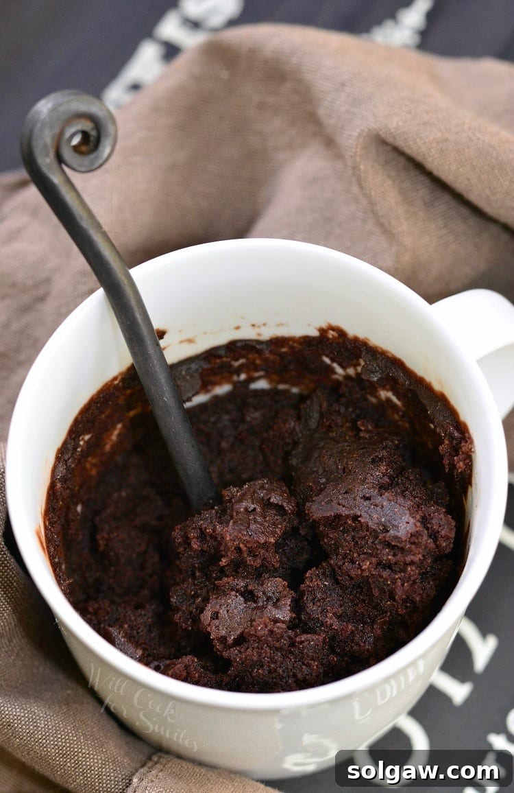 Chocolate cake in a white coffee mug with a spoon inside cup