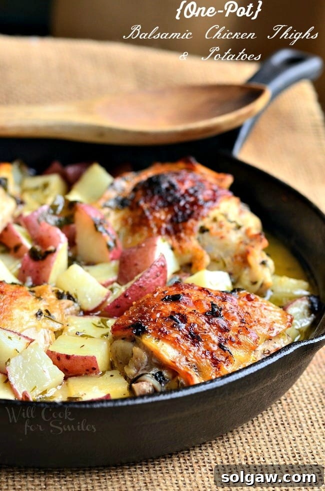 Balsamic Chicken Thighs & Potatoes in a cast iron skillet with a wooden spoon over the top, highlighting the rich sauce.