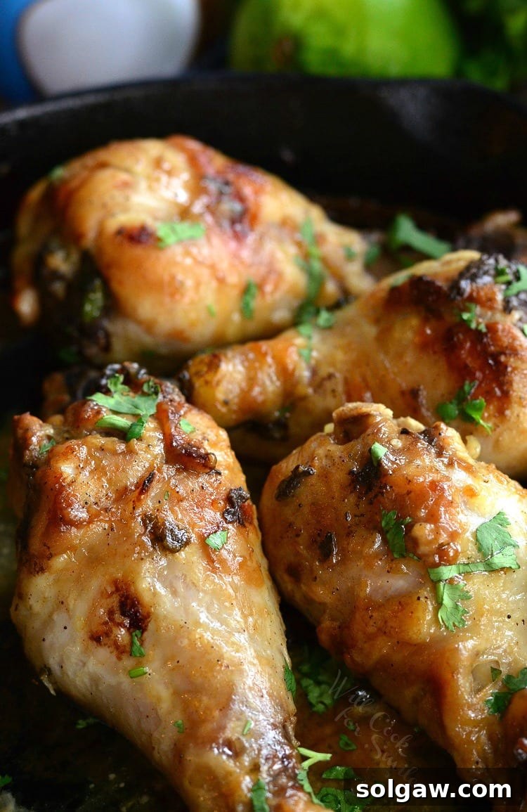Close-up of baked Coconut Lime Chicken Drumsticks in a cast iron skillet, golden brown and garnished with fresh cilantro.