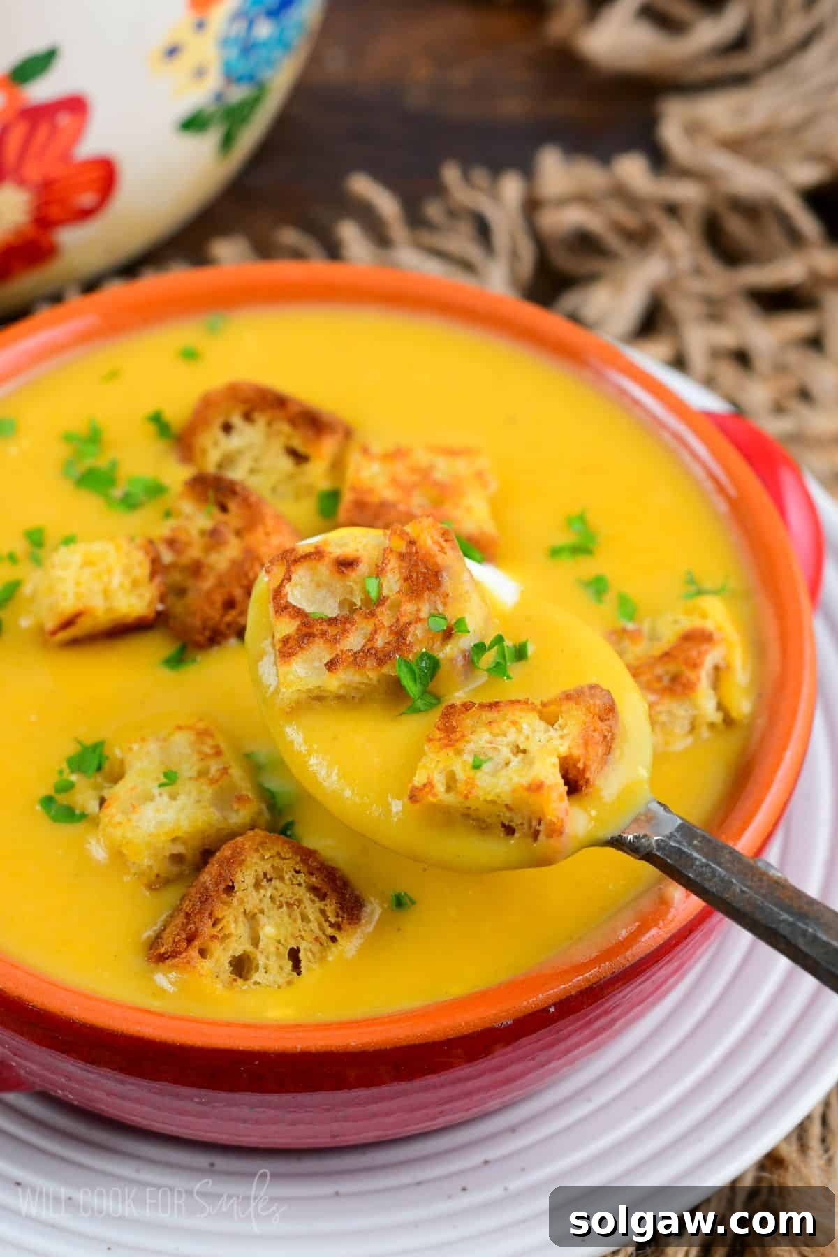 A comforting bowl of Butternut Squash Potato Soup, garnished with two golden croutons, ready to be enjoyed.