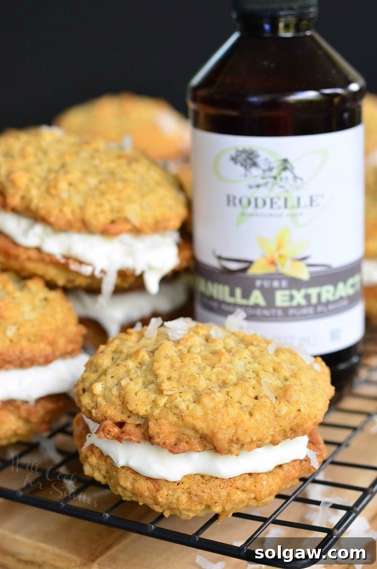 Coconut Oatmeal Cookie Sandwiches on a cooling rack with a bottle of pure vanilla extract in the background