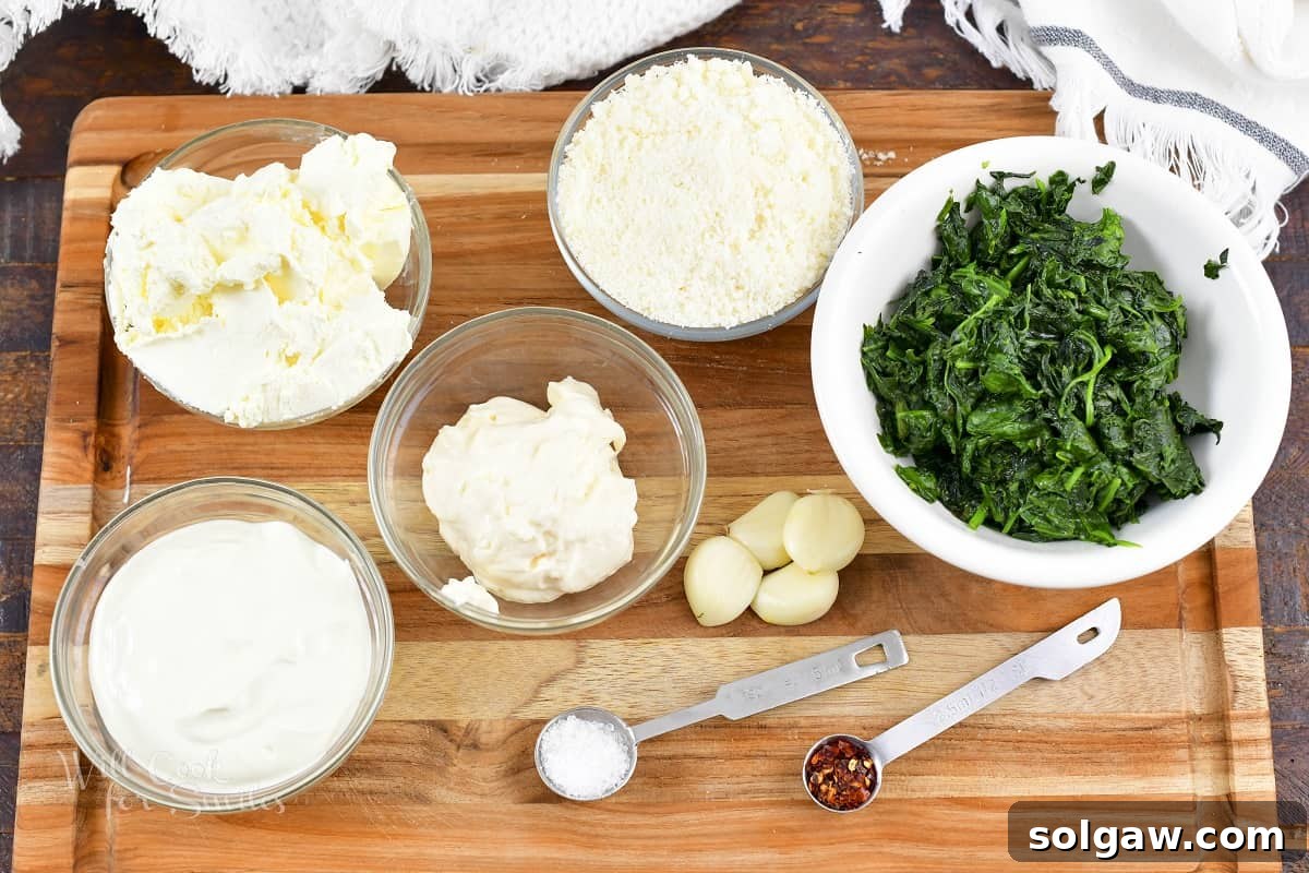 Ingredients for Garlic Parmesan Spinach Dip laid out on a wooden cutting board.