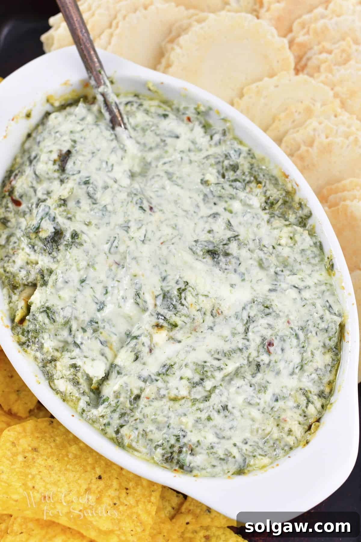 Top-down view of the baked Garlic Parmesan Spinach Dip, bubbly and golden brown, in its baking dish.
