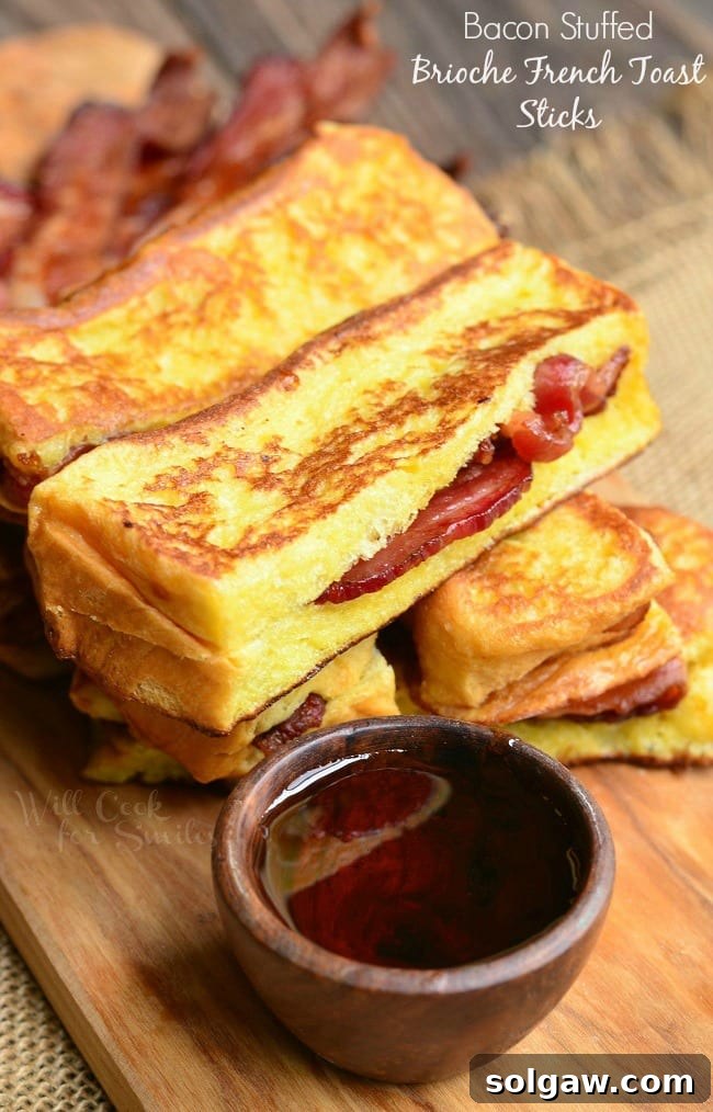 Golden Honey Delights 13 Bacon Stuffed Brioche French Toast Sticks on a cutting board with a small wooden bowl of syrup.
