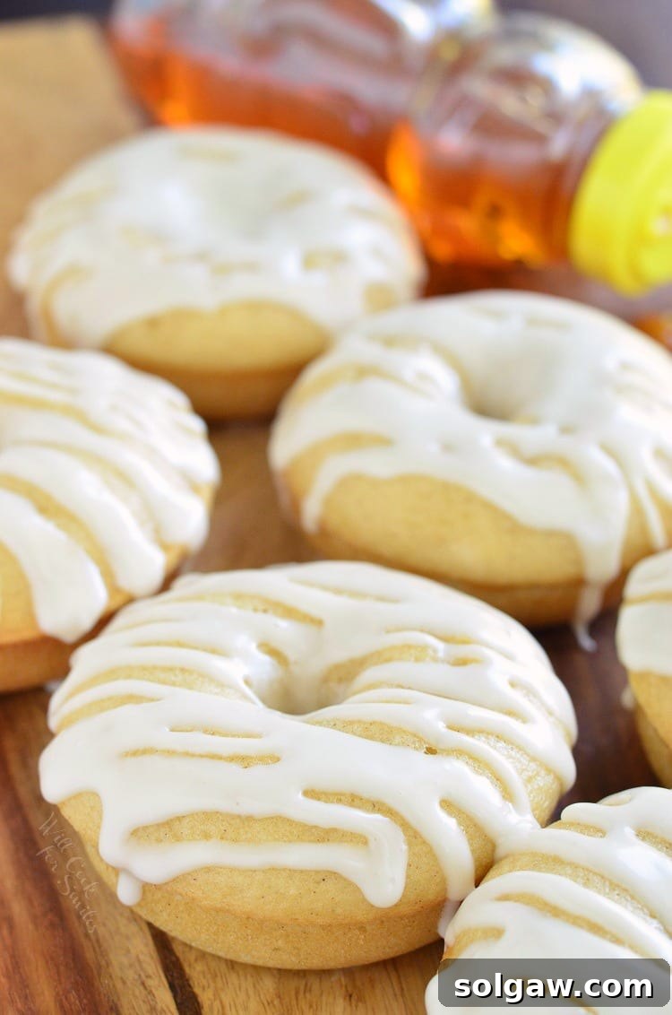Golden Honey Delights 7 An inviting arrangement of golden baked honey doughnuts, stacked artfully on a wooden board, with a blurred honey bottle in the background, emphasizing their homemade charm.