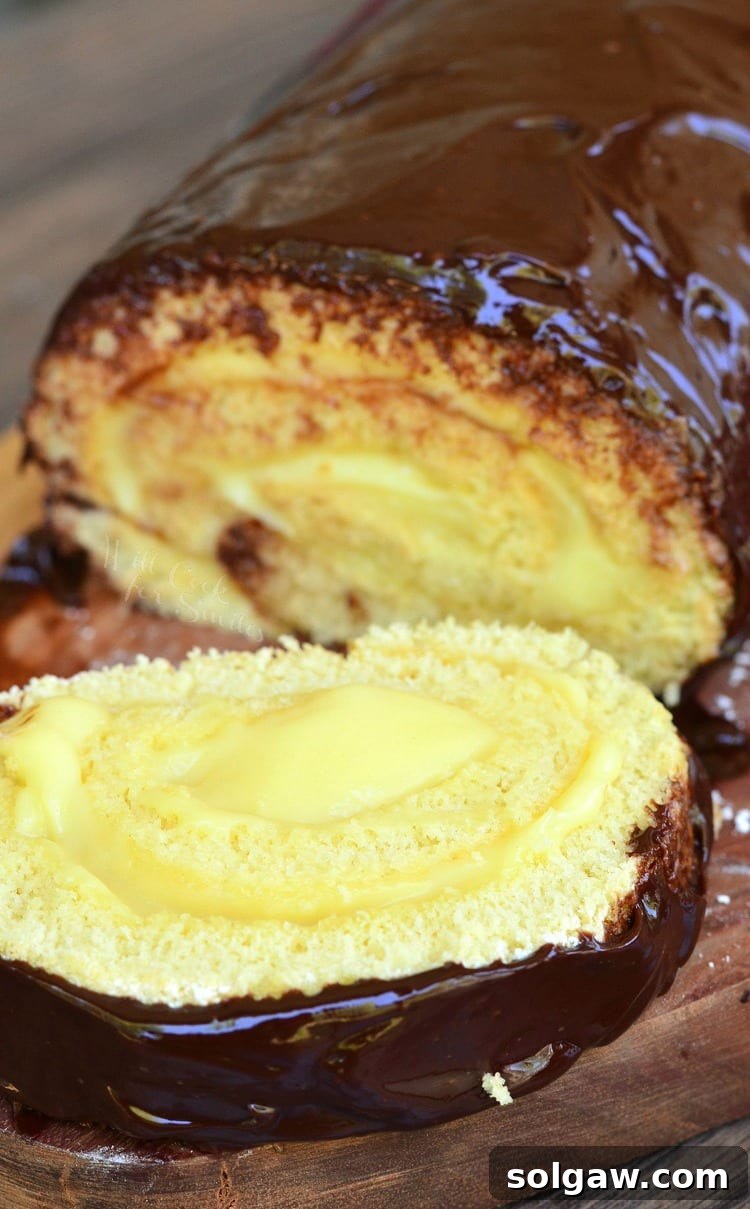 Boston Cream Cake Roll with a slice on a wood cutting board 