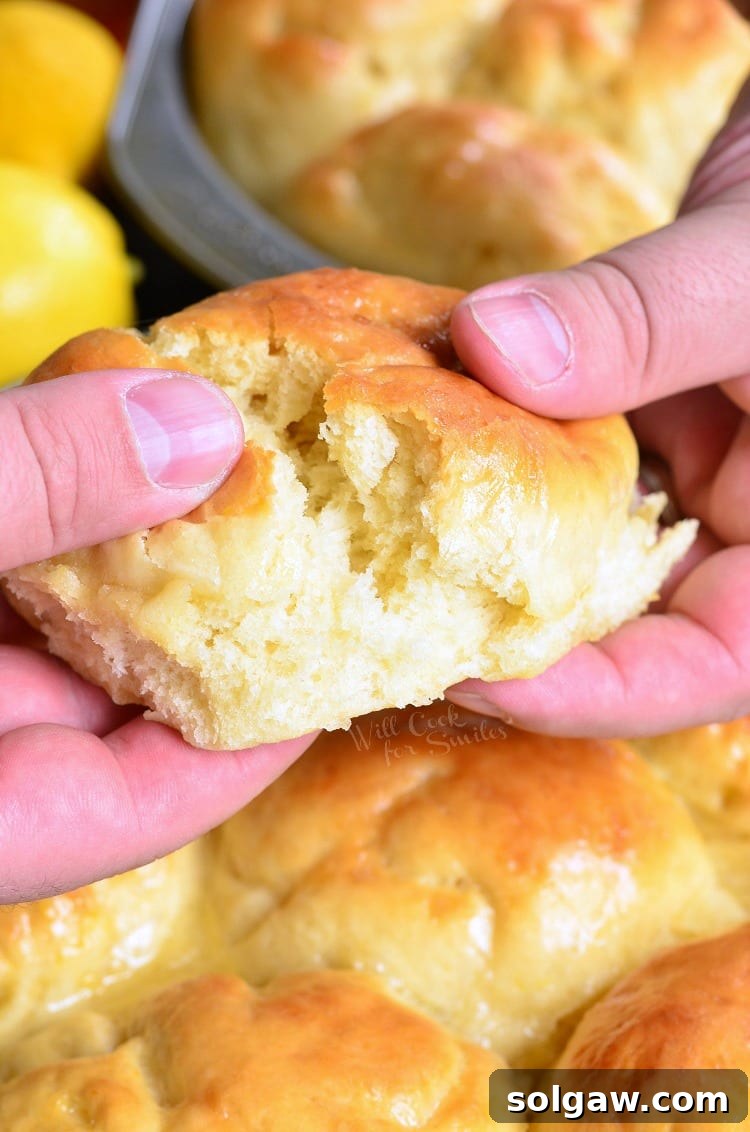 Tearing a fluffy Honey Lemon Dinner Roll in half, revealing its soft interior