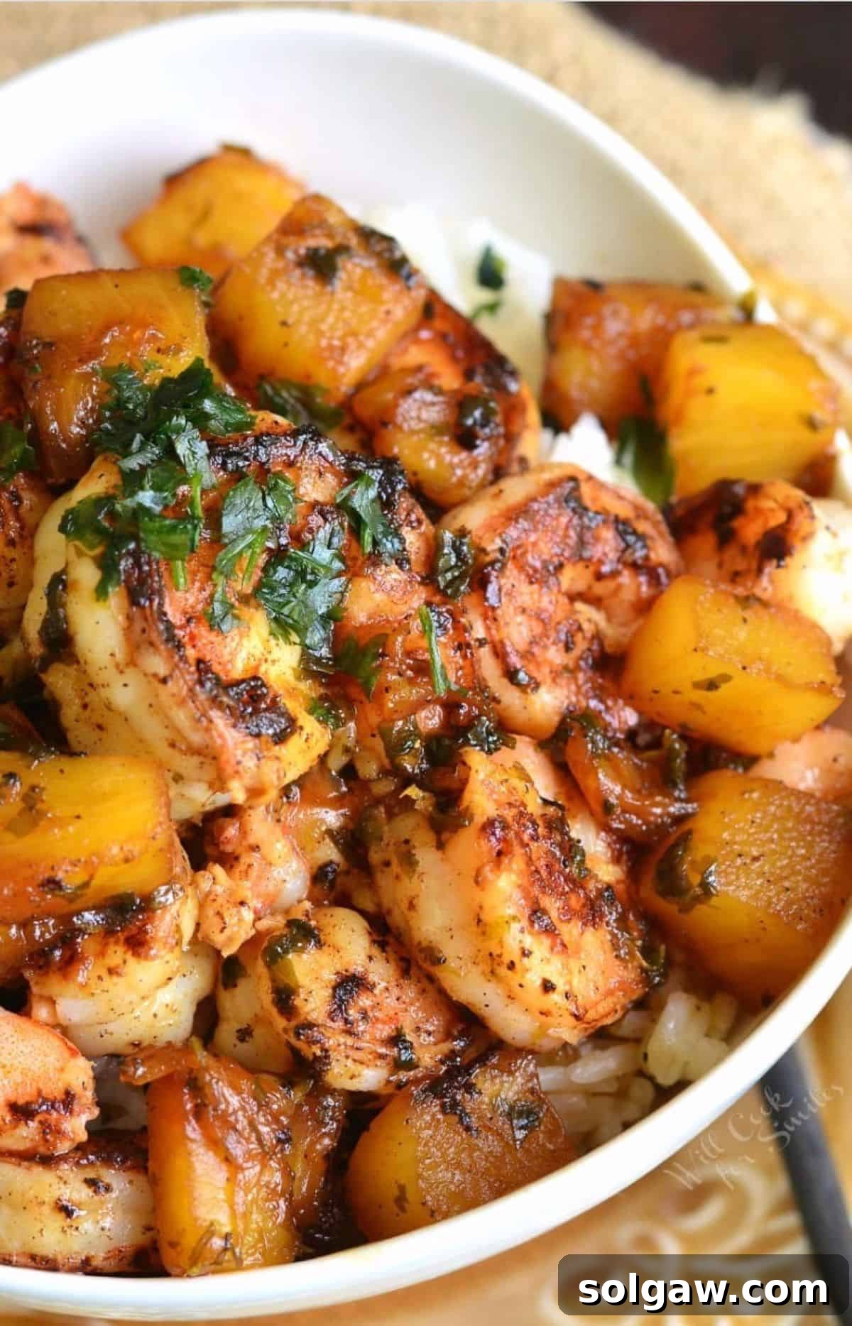 Island Shrimp Rice Bowl 2 A vibrant Tropical Shrimp Rice Bowl, garnished generously with fresh cilantro, showcasing succulent seared shrimp and juicy pineapple chunks over fluffy rice.