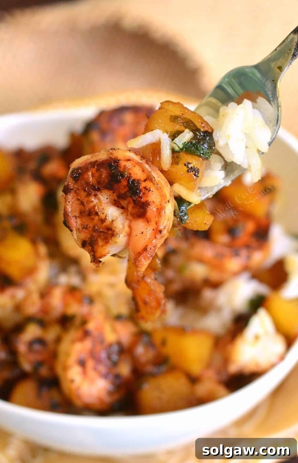 Island Shrimp Rice Bowl 8 A fork lifts a succulent piece of seared shrimp and a golden-brown pineapple chunk from a Tropical Shrimp Rice Bowl, ready to be enjoyed.