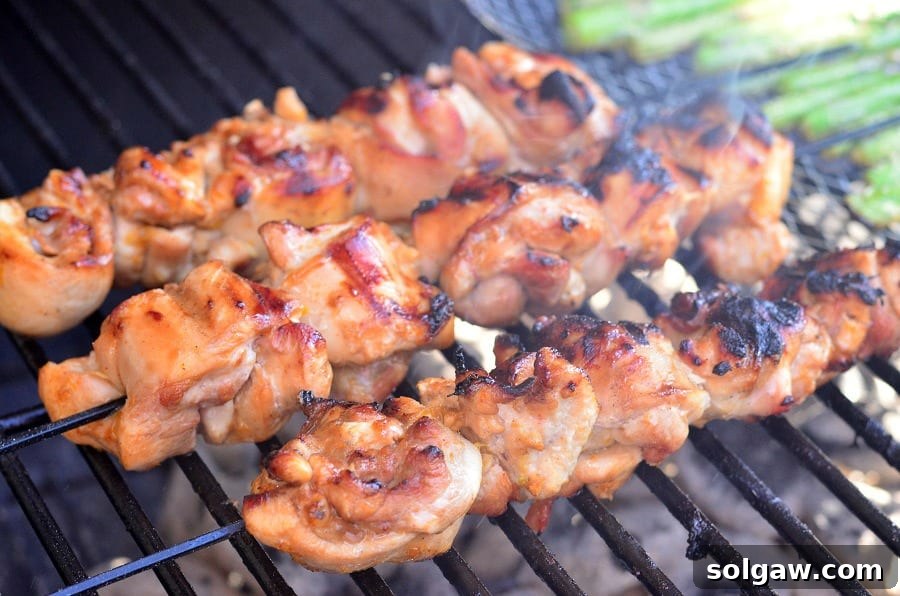 Orange Glazed Chicken Skewers 4 Three perfectly cooked chicken thigh kebabs sizzling on a charcoal grill, showcasing their golden-brown char and succulent appearance.
