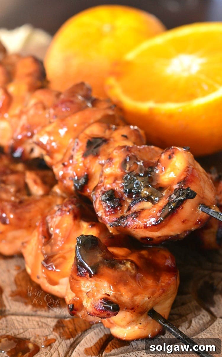 Orange Glazed Chicken Skewers 9 A beautifully composed shot of Sticky Orange Chicken Kebabs, artfully stacked on a cutting board, garnished with a vibrant lemon wedge.