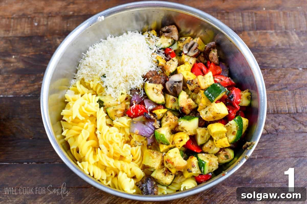 Smoky Grilled Veggie Pasta Salad 4 Grilled vegetable pasta salad ingredients in a metal bowl on a wood surface, before mixing.