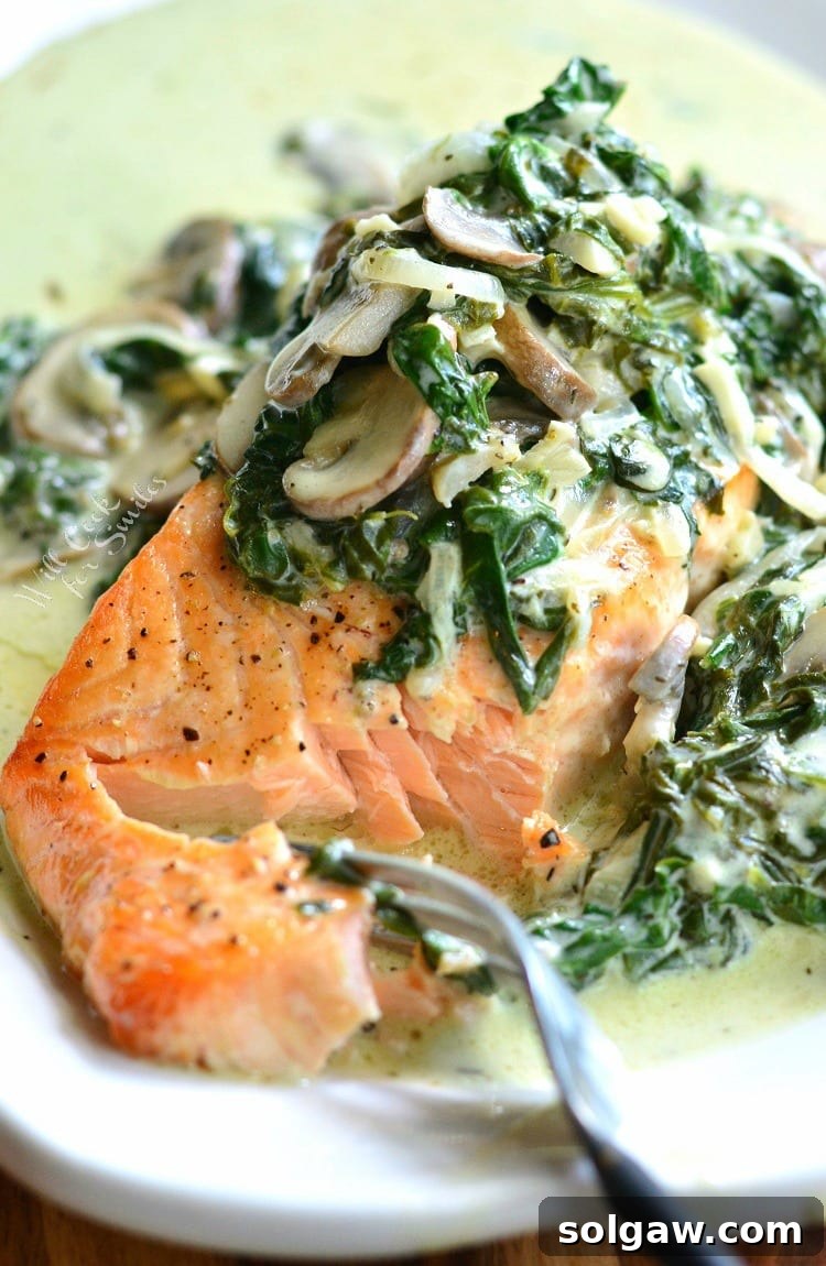 Emerald Florentine Salmon 3 Close-up of a plate of Salmon Florentine, showing a fork taking a bite of creamy spinach and mushroom alongside the salmon.
