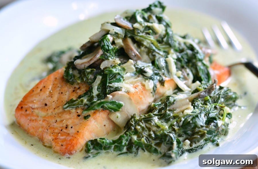 Emerald Florentine Salmon 4 Horizontal shot of Salmon Florentine on a white plate, showcasing the baked salmon topped with spinach and mushroom cream sauce.