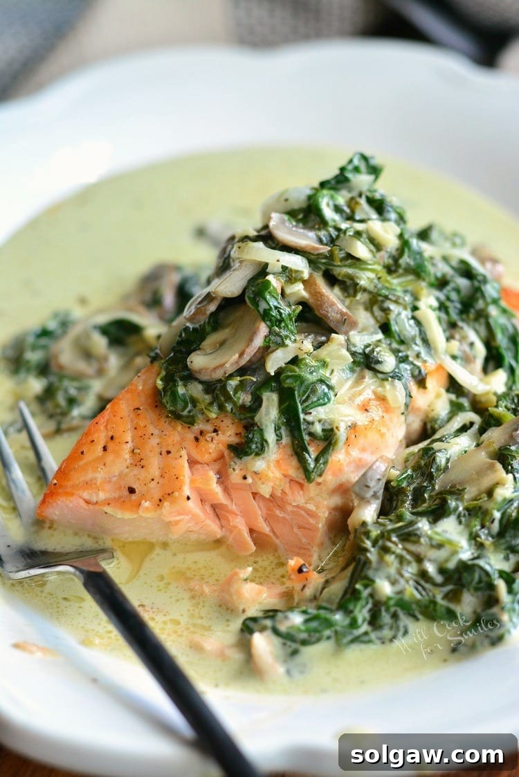 Emerald Florentine Salmon 5 A close-up view of Salmon Florentine on a white plate, with a portion already removed, highlighting its creamy texture.