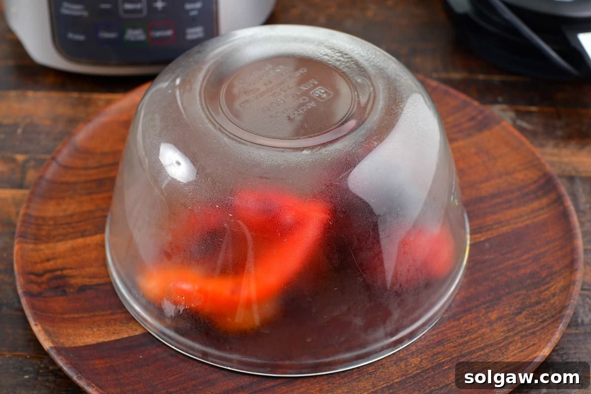Hot roasted red bell peppers covered with a bowl to steam, making the skin easy to remove.