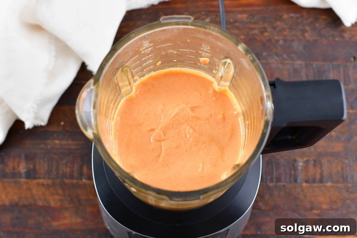 Smooth, blended roasted red pepper hummus spinning inside a food processor bowl, showing its creamy texture.