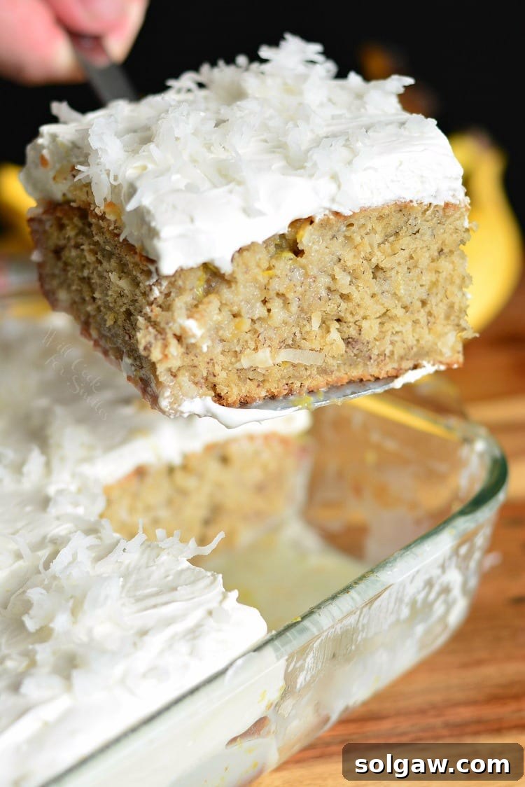 Lifting a slice of Lemon Coconut Banana Poke Cake from a baking pan