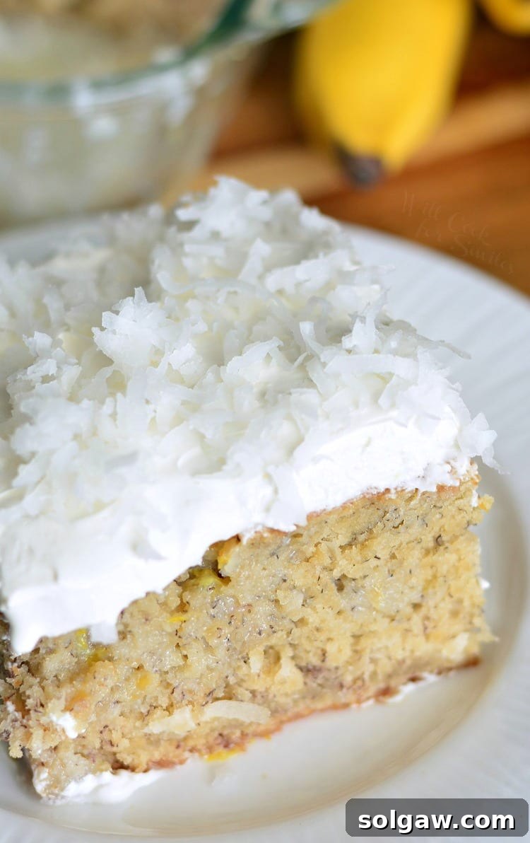 Lemon Coconut Banana Poke Cake on a plate, garnished with more coconut